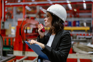 Woman engineer manager standing at steel production factory. Female inspector wears safety hard hat...