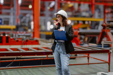 Woman engineer manager standing at steel production factory. Female inspector wears safety hard hat...