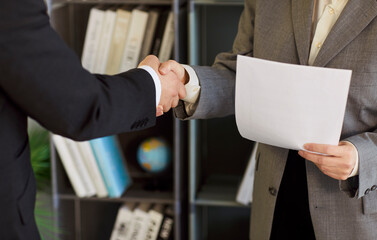 Two business people exchanging a handshake. Two unrecognizable people in formal suits shake hands...
