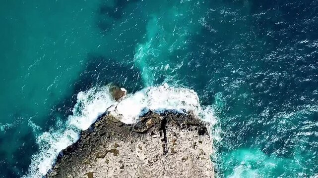 A drone shot from above as the waves crash onto the shore