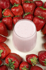 Strawberry sweet milkshake in a glass among fresh ripe strawberries.