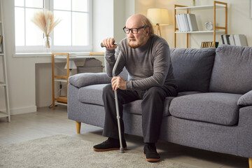 Senior man at home, lonely old grey haired man sitting alone on sofa, looking, thinking suffering...