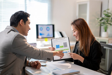 Fototapeta premium A man and a woman are sitting at a desk with a white board and a projector