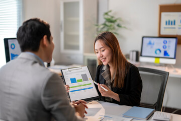 A man and a woman are sitting at a desk with a presentation in front of them