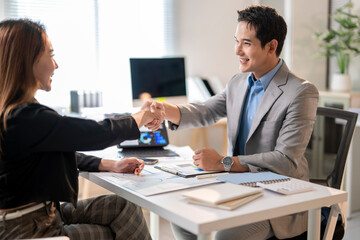 A man and a woman shaking hands in a business meeting