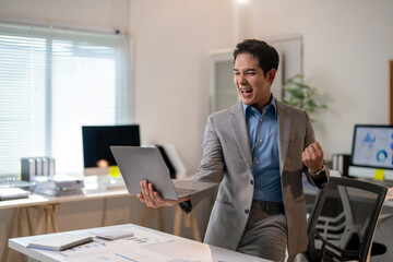 A man in a suit is holding a laptop and smiling