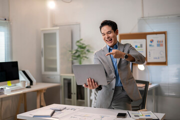 A man in a suit is pointing at a laptop computer