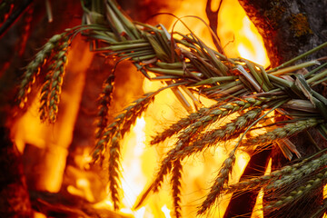 Close-up of a traditional braided wheat ornament burning in vivid orange flames, surrounded by branches and intense firelight.