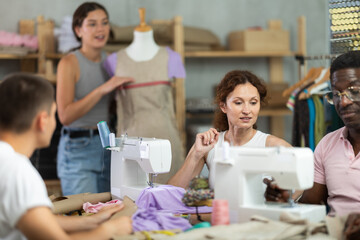 In sewing workshop coterie school, people learn craft of tailor. Participants chatting, work with mannequin, sewing. Interest group, activities, hobbies, vocational training