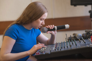 Young woman mixing live sound. Girl recording a song in the studio. 