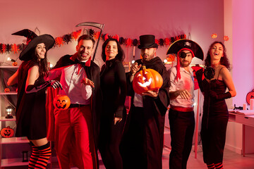 Group portrait of friends in costumes celebrating a halloween party together at home at night. Fun...