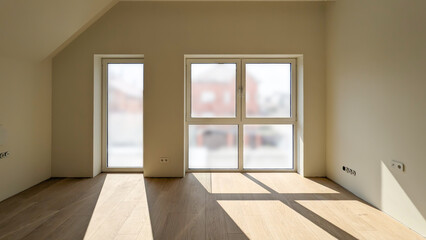 Empty room after renovation in a private house. The room has large windows to the floor, through which a lot of light passes.