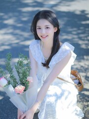 Young woman in white dress holding flowers outdoors.