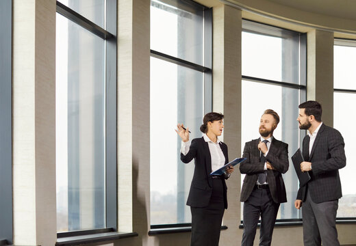 Confident realtor presenting commercial property to potential investors in office building. Professional business people discussing opportunities, analyzing investment potential and location benefits.