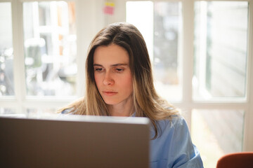 Focused woman freelancer working online on laptop, sitting at desk at home, look at screen, typing,...