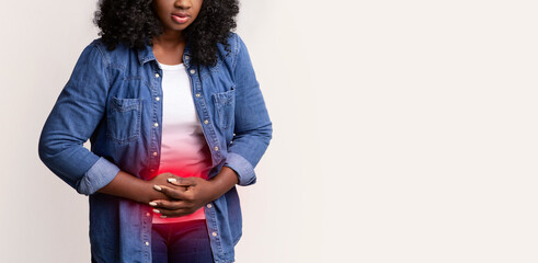 Upset african american young woman suffering from abdominal pain over grey studio background,...
