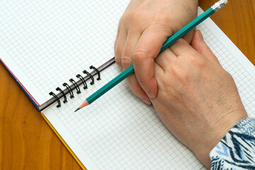 Creative hands poised to write in a blank notebook on a wooden table