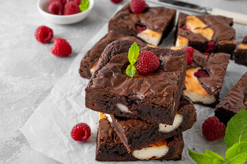 Cheesecake brownies with raspberry on a gray concrete background. Delicious dessert