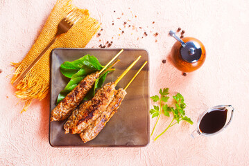 Grilled Lula kebab on skewers with spices in a claim plate on a table