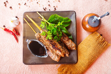 Grilled Lula kebab on skewers with spices in a claim plate on a table