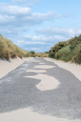 A Winding Path That Goes Through Sandy Dunes Beneath Overcast Cloudy Skies Above