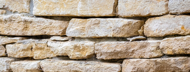 Close up of rough stone masonry with various sized and shaped natural stones creating a unique texture and rustic pattern for background