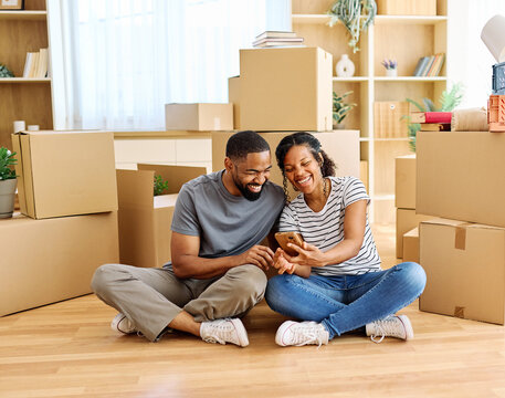 Portrait of a young couple unpacking, moving in and relocation to a new apartment, happy young couple  taking a selfie photo with a smartphone, family new beginning sitting on the floor
