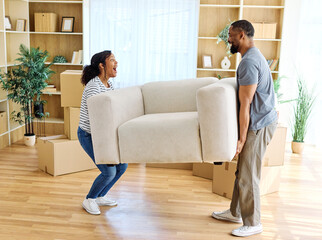 Portrait of a young couple unpacking, moving in and carrying a sofa couch around in a new...