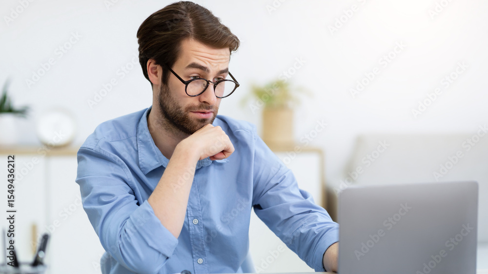 Poster surpirsed business guy in eyewear looking at laptop having computer problem sitting at desk in moder