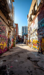 Fototapeta premium Urban alleyway canvas vibrant graffiti and weathered charm showcasing the city's artistic pulse and hidden stories beneath the vast clear blue sky