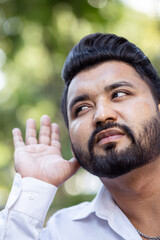 Curious and questioning young South Asian Indian man listening to bad news with negative expression, concept image for ear care, hard of hearing, fake news, rumors