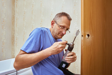 Woodworker tightens spade bit in drill chuck using chuck key.
