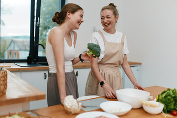 Happy middle age woman enjoying healthy cooking with fresh vegetables, promoting active wellbeing...