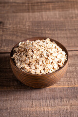 Raw oats in a wooden bowl on a wooden background. Organic food concept. 