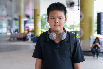 Thai teen boy wearing headphones with city taxis in background