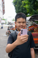 Thai boy with headphones standing by tuk tuk taxis