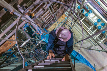 The topview male worker down the ladder is for inspection stainless steel tank © chitsanupong