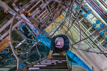The topview male worker down the ladder is for inspection stainless steel tank © chitsanupong
