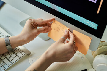 Caucasian young adult woman attaching sticky note with handwritten neural network development task...
