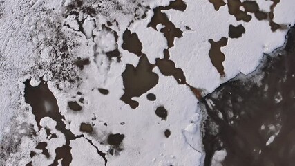 Top-down aerial view of melting snow and fragmented ice formations near Borgarfjörður Bay, Iceland, showing abstract natural patterns and thawing seasonal textures. - Powered by Adobe