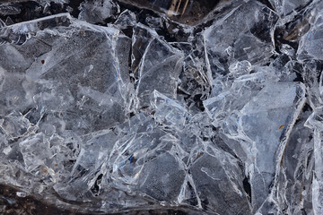Cracked ice on a puddle texture background cracks and shards on a dark background