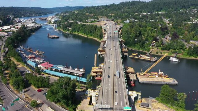 4K aerial drone footage of Abernethy Bridge and I-205 highway over the Willamette River, connecting Oregon City and West Linn, Oregon, with construction barges, traffic, and scenic surroundings