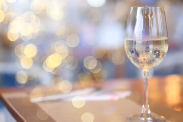 a glass of white wine, a background under the summer sun, a bokeh and sun glare, a blurred abstract...