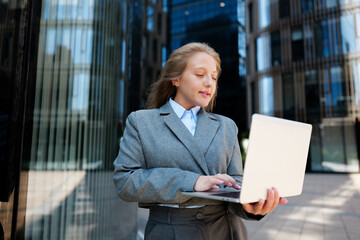 Business professional engaged in work outside modern office buildings during a sunny day in a...