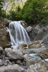 Serene Waterfall Cascading Over Rocks Surrounded by Lush Green Foliage