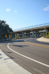 Curved Road Passing Under Modern Overpass with Blue Sky
