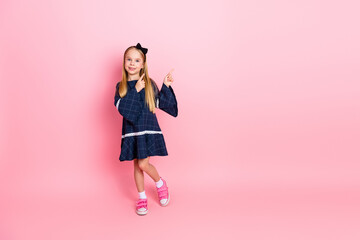 Charming Young Girl in a Stylish Dress Standing Against a Vibrant Pink Background, Expressing...