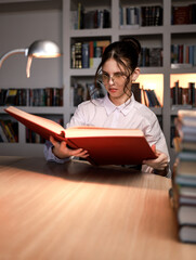 A girl reads a huge historical book in an atmospheric setting.