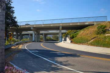Curved Road Passing Under Modern Overpass with Blue Sky
