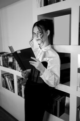 A girl in the library with a book.
